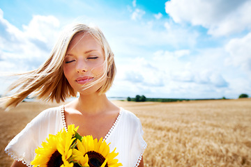 Image showing Freedom, nature and calm woman with a sunflower on a wheat field for travel or vacation. Peace, face and female person in nature with a flower in countryside for holiday, journey or adventure outdoor