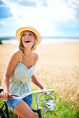 Image showing Woman laughing on bicycle in the countryside, happiness and travel on journey or thinking outdoor. Funny, bike and excited person smile at field on transport, freedom and cycling in nature in summer