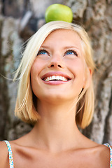 Image showing Woman, face and thinking with smile for apple by tree in natural nutrition, diet or health and wellness in nature. Female person with organic green fruit in wonder for healthy vitamin, snack or meal