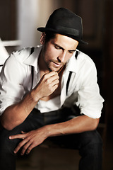 Image showing Man, hipster and thinking about fashion, ideas or choice of clothes in dark background. Clothing, decision and creative person or model sitting and planning outfit with vintage hat and retro style