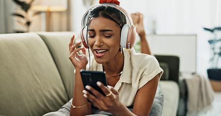 Image showing Phone, music and happy woman singing on sofa in home, dance and listening to audio. Smartphone, excited Indian person on headphones for radio, sound or freedom in living room on mobile app technology