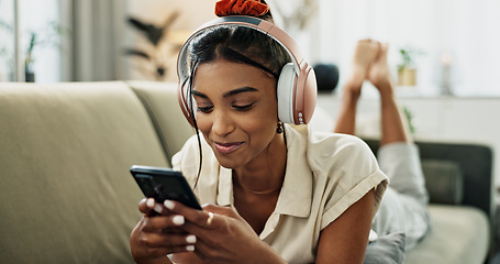 Image showing Phone, music headphones and happy woman on sofa in home, listen to audio and video app to relax. Smartphone, sound and Indian person on radio or typing on social media in living room on mobile tech