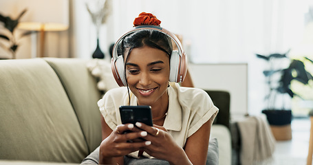 Image showing Smartphone, music headphones and happy woman on sofa in home, listening to audio or video app to relax. Phone, sound and Indian person on radio or typing on social media in living room on mobile tech