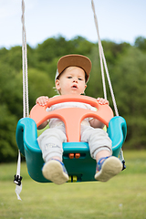 Image showing Adorable little happy Caucasian infant baby boy child swinging on playground outdoors.