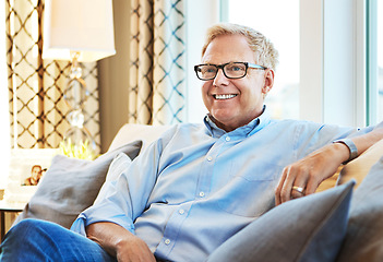 Image showing Thinking, happy or mature man on sofa to relax with calm on living room couch at home for resting. Ideas, glasses or senior male person with smile, peace or wellness in retirement, lounge or house