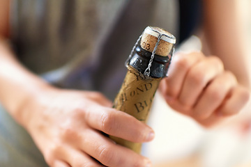 Image showing Hands, person and open cork on bottle of wine, champagne and alcohol for party, celebration and congratulations for special event. Closeup, drink and pop muselet, wire cage and cap of liquor beverage