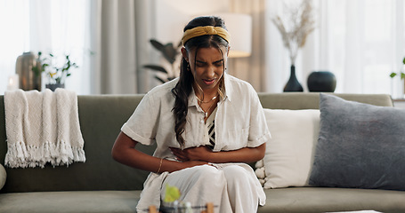 Image showing Woman, stomach and pain on sofa in home for gut health, indigestion and anxiety of gastric virus. Stress, menstruation and sick indian girl with ibs emergency, constipation or crisis of endometriosis