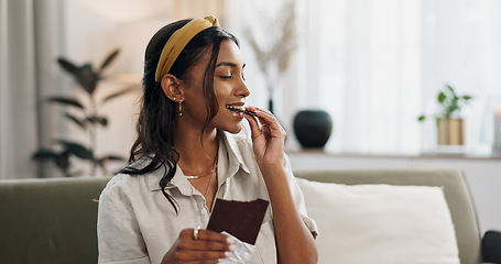 Image showing Home, relax and woman with chocolate bar, smile and eating with candy, hungry and dessert. Person, apartment or girl on a sofa, candy or sweet treats with a snack, nutrition or diet plan with cacao