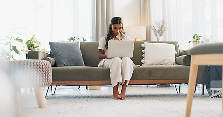 Image showing Woman, laptop and typing on sofa for communication, email or social media scroll in living room of home. Indian, girl and pc for freelance web search, streaming or technology with internet in lounge