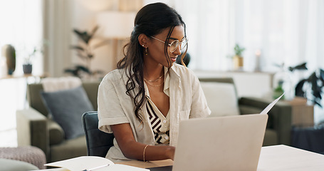 Image showing Laptop, remote work and woman reading for research in the living room of modern apartment. Smile, technology and young Indian female freelancer working on creative project with computer at home.