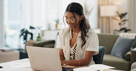 Image showing Laptop, remote work and woman typing for research in the living room of modern apartment. Smile, technology and young Indian female freelancer working on creative project with computer at home.