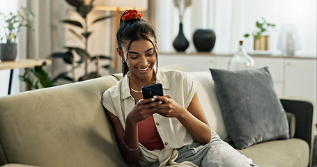 Image showing Woman, smile and scroll on cellphone, social media post and update subscription app on sofa at home. Happy indian girl, smartphone and download mobile games, reading notification and chat to contact