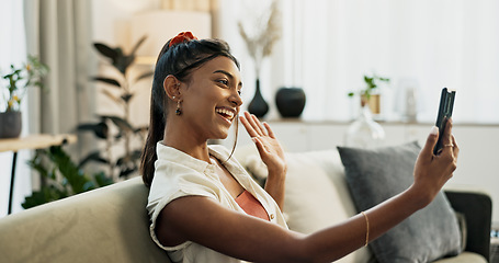 Image showing Phone, happy or Indian woman on a video call on a sofa or couch to relax in living room or apartment. Wave, communication or excited person on mobile conversation with smile in lounge of modern home