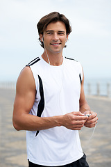 Image showing Man, smile and earphones in workout for music, podcast and song on run, exercise and cardio. Male athlete, hearing and streaming radio, audio and sound by ocean, outdoors and inspiration for fitness