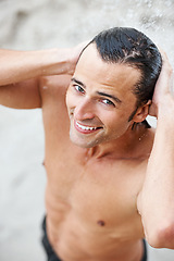 Image showing Man, smile and water shower in outdoors, beach and hydrate or clean after swimming, relax and travel. Happy male person, portrait and vacation for fun, water splash and fresh on holiday or getaway
