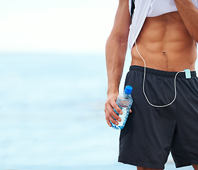 Image showing Man, fitness and abs with water bottle in outdoor, mockup and space by inspiration for wellness. Male athlete, pride and confident for bodybuilding by ocean, sea and progress by exercise and workout