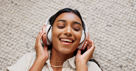 Image showing Headphones, happy and young woman on the carpet on the floor listening to music or album. Smile, calm and Indian female person streaming podcast, radio or playlist and chilling in living room of home