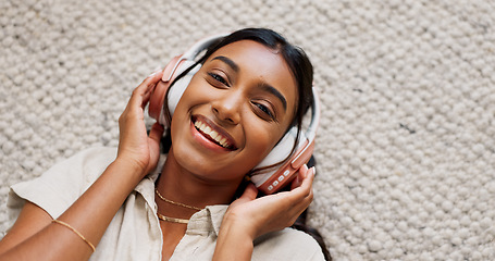 Image showing Headphones, smile and portrait of woman in the living room relaxing on mat on floor. Happy, calm and Indian female person listen to podcast, radio or music and chilling in lounge at home from above.