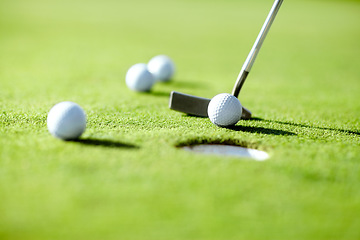 Image showing Closeup, golf and ball with club for shot in hole for practice, exercise or wellness to relax on grass. Sports, course or target for challenge on field in summer for competition, recreation or hobby