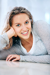 Image showing Woman, portrait and floor lying smile in home for cheerful friendly, calm or feminine look. Female person, happy face and hand on ground for attractive, lazy weekend joy or positive relax in Canada