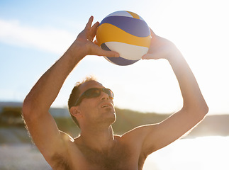 Image showing Beach, sunshine and sports man in volleyball game, competition or playing nature challenge, practice or workout. Sky, summer flare and volley ball player, athlete or person in outdoor match contest