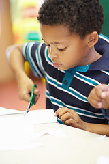 Image showing Boy, classroom and scissor for cutting paper with learning, thinking and development in kindergarten. African child, education and ideas at preschool academy for skills, scholarship or knowledge