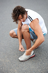 Image showing Man, fitness and tie sneakers on road outdoor for running, workout and start sports performance. Runner, earphones and lace shoes on feet to prepare for exercise, cardio and marathon in city street