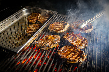 Image showing Rib-eye steaks cooking on flaming grill.