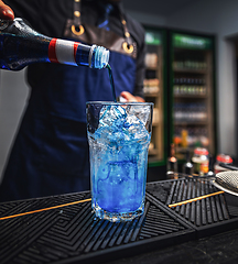 Image showing Bartender pours blue liquor