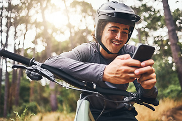 Image showing Fitness, bike and phone with man texting and cycling in a forest, happy and relax in nature with cyclist. Gps, internet and map with sports male enjoying freedom and easy online direction in woods