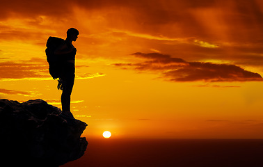 Image showing Dark silhouette, mountain travel and sunset on hiking adventure in nature, sky orange while trekking with backpack and freedom on cliff. Person on holiday in Africa walking on summer journey