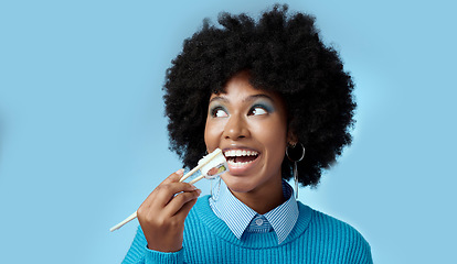 Image showing Happy, food and black woman with sushi in a studio eating with japanese chopsticks with mockup space. Healthy meal, smile and african girl with a afro enjoying delicious sashimi with blue background.