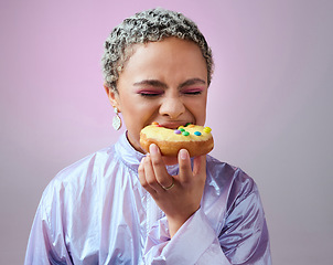 Image showing Food, studio and woman is eating a donut cake with eyes closed enjoying sweet icing and sugar pastry alone. Hungry young girl on a fast food diet with a big bite on a doughnut snack as a cheat meal