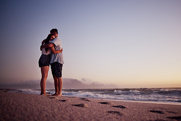 Image showing Love, beach and footprints in the sand with couple at sunset for support, hug or happy on Cancun summer vacation. Trust, goals and hope with man and woman by the sea on holiday for travel and romance
