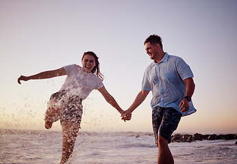 Image showing Beach water splash, couple and happy people together feeling love and fun in summer at sunset. Girlfriend and boyfriend holding hands in the ocean waves and sea on a vacation with quality time