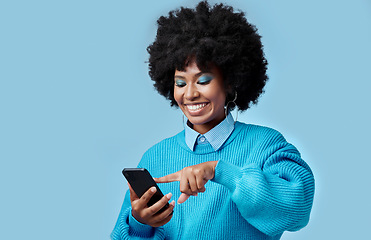 Image showing Happy, phone and black woman reading a blog on an internet website in a studio with mockup space. Happiness, smile and african girl networking on social media on as smartphone with a blue background.