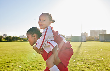 Image showing Girl soccer and team friends on field enjoying match game leisure break with fun piggyback ride. Happy, young and excited football children relax together on sport ground in athlete uniform.