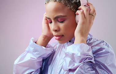 Image showing Fashion, headphones and black woman listening to music with retro vaporwave clothes on studio pink background. Gen z girl model with color cosmetics and audio technology for youth mockup advertising