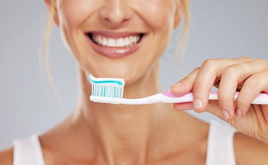 Image showing Toothpaste, hand and toothbrush in morning smile with clean teeth, wellness and dental healthcare in mockup studio background. Zoom of mouth cleaning, cosmetic beauty and healthy self care routine