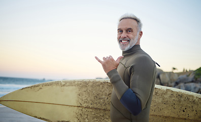 Image showing Summer, surfing and portrait of old man at the beach in the morning. Retired senior man with surfboard, hand sign and smile on face ready to surf at sunrise. Ocean, hobby and water sport in Australia