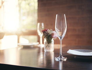 Image showing Empty glass on table for wine, champagne or alcohol at dinner in romantic restaurant, home or diner. Luxury, lunch or supper with crystal wine glass, plate and flower for reception, banquet or meal