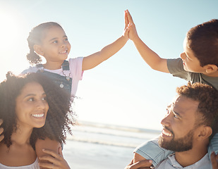 Image showing High five, kids and parents at the beach on vacation, holiday and enjoying the sunny day. Family, father and mother on a day outside by ocean with the children on the backs, playing and smile.