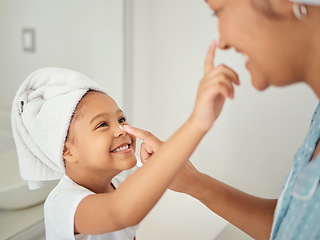 Image showing A happy Mom, smiling child using cream and teaching skincare beauty routine to girl in a bathroom. Mother helping her daughter to learn to help her skin, hair and body healthy with self care products