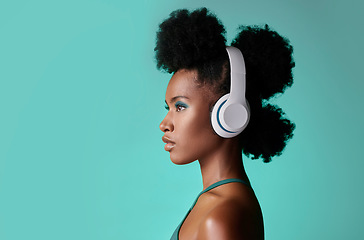 Image showing Music, designer headphones and black woman thinking while listening to podcast against a blue mockup studio background. African model streaming audio from radio with creative idea nd mock up space