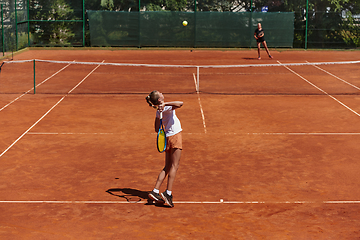 Image showing Young girls in a lively tennis match on a sunny day, demonstrating their skills and enthusiasm on a modern tennis court.