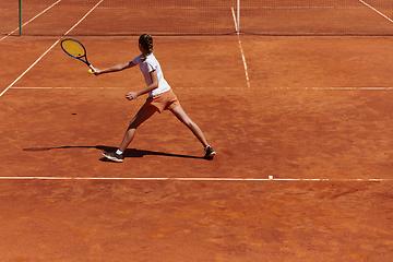 Image showing A young girl showing professional tennis skills in a competitive match on a sunny day, surrounded by the modern aesthetics of a tennis court.