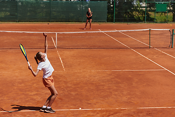 Image showing Young girls in a lively tennis match on a sunny day, demonstrating their skills and enthusiasm on a modern tennis court.