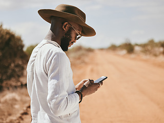 Image showing Dessert dirt road, black man and phone text in nature on a vacation lost and waiting for a lift. 5g internet, mobile and web app usage of a person from Madrid wait for a taxi to travel in summer