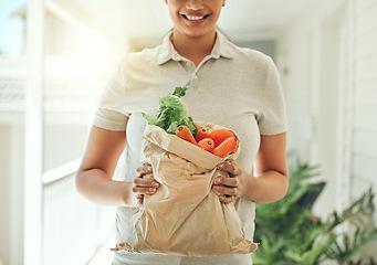 Image showing Healthy food, delivery and vegetables in brown grocery paper bag for clean vegan diet with fresh organic ingredients in hands of woman standing at home. Nutrition, vegetarian and health of a female
