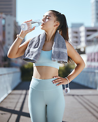 Image showing Woman with water bottle, and fitness in the city, rest and drinking with towel on summer morning in Australia. Health, exercise and girl runner taking time for resting during outdoor urban workout.